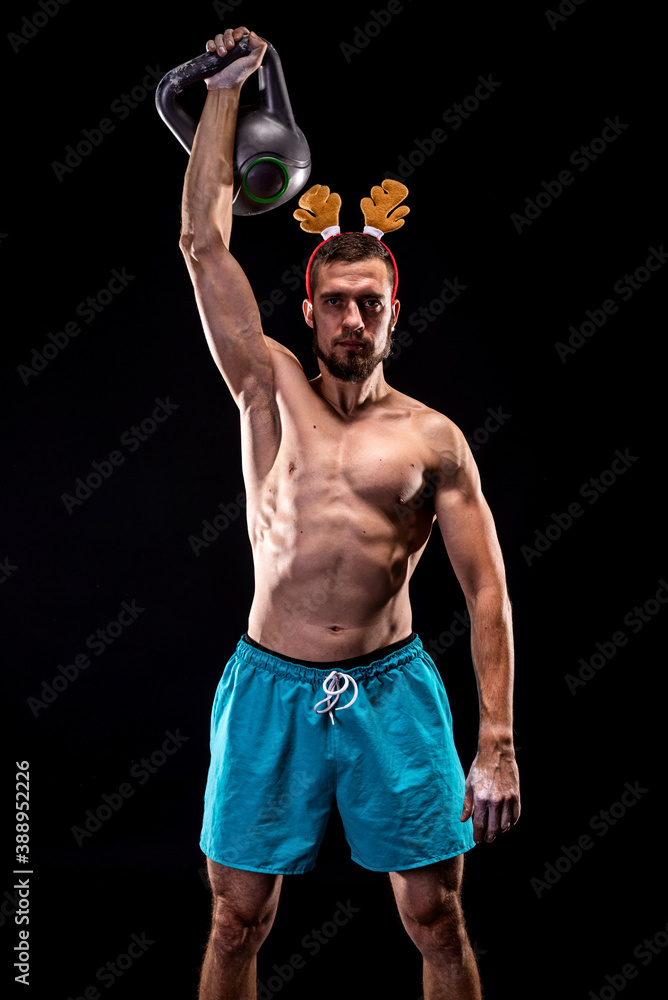 Athletic man in deer horns trains with a kettlebell.