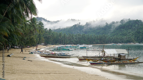 Fototapeta Naklejka Na Ścianę i Meble -  Boat anchored at the Port Barton tropical beach with palm trees on Palawan island in the Philippines.