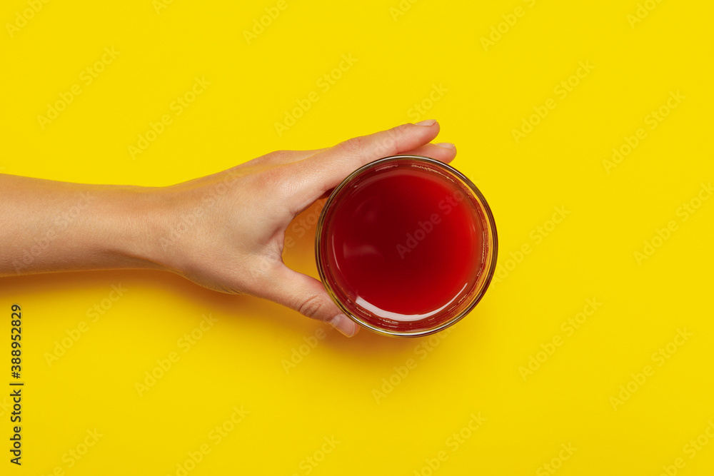 Female hand hold glass of apple juice on yellow background Female hand hold glass of apple juice on yellow background