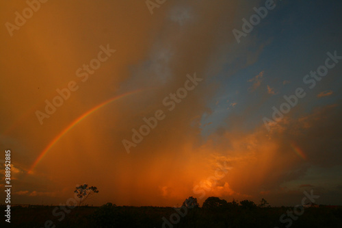 Twilight with a rainbow against a background of orange clouds and blue sky