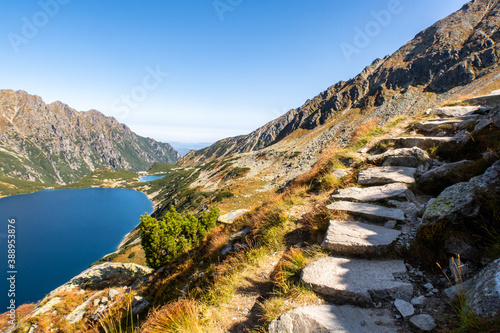 Fototapeta Naklejka Na Ścianę i Meble -  Stony mountain trail leading to Szpiglasowy Wierch Mount in Tatra Mountains, with crystal blue mountain lake Wielki Staw Polski in Five Polish Ponds Valley below, mountain autumn landscape, Poland