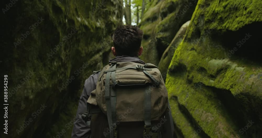 A man is walking through a gorge. He is carrying a large backpack. Shooting from behind. Hiking in the mountains. 4K DCI A man is walking through a gorge. He is carrying a large backpack. Shooting from behind. Hiking in the mountains. 4K DCI
