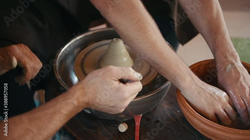 Old experienced guy teach man how to use potter's wheel to create handmade clay product. photo