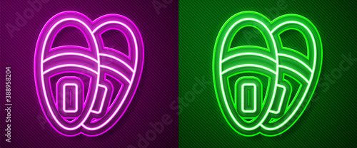 Glowing neon line Slippers icon isolated on purple and green background. Flip flops sign. Vector.