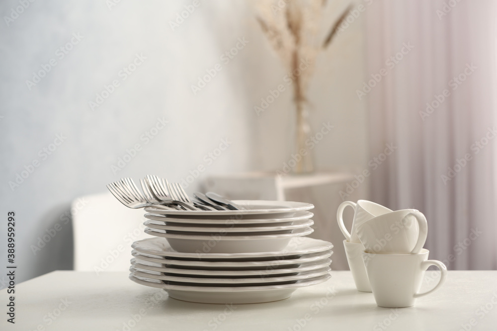 Set of clean dishware and cutlery on white table indoors. Space for text Set of clean dishware and cutlery on white table indoors. Space for text