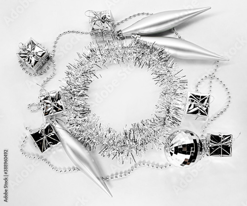 Round circle of silver tinsel, christmas pine toys, chain of balls, beads. New year decorations on a white background. Concept