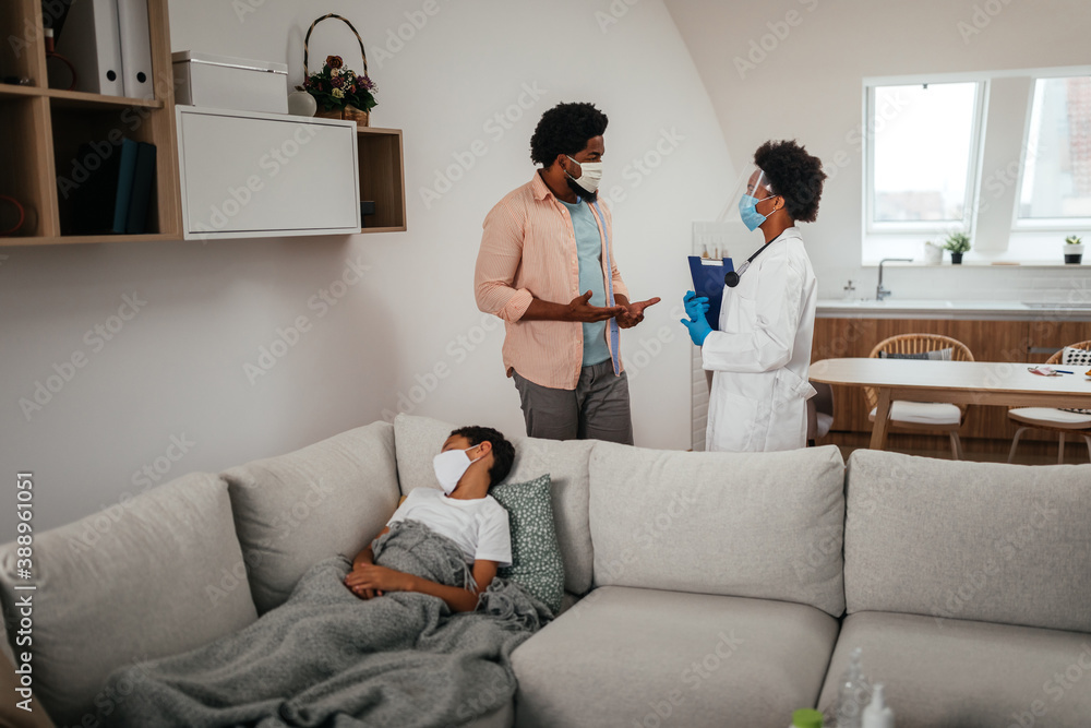Fototapeta premium Doctor having consultation with man whose son is sick and lying on bed near them