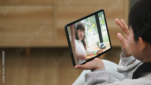 Cropped shot of young woman sitting on sofa in living room and talking with her friend via video call. © Prathankarnpap