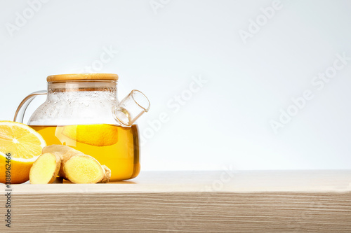 Teapot of ginger tea with lemon on wooden table with place for text.