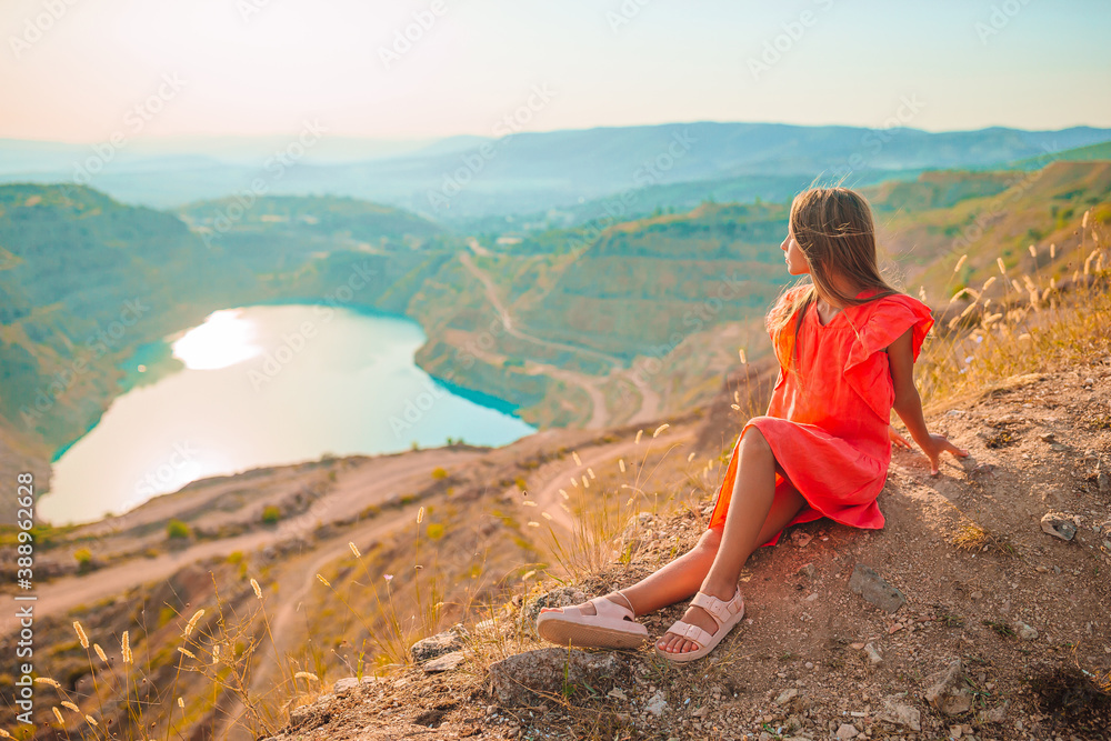 Little girl near the lake at the day time with amazing nature on background Little girl near the lake at the day time with amazing nature on background