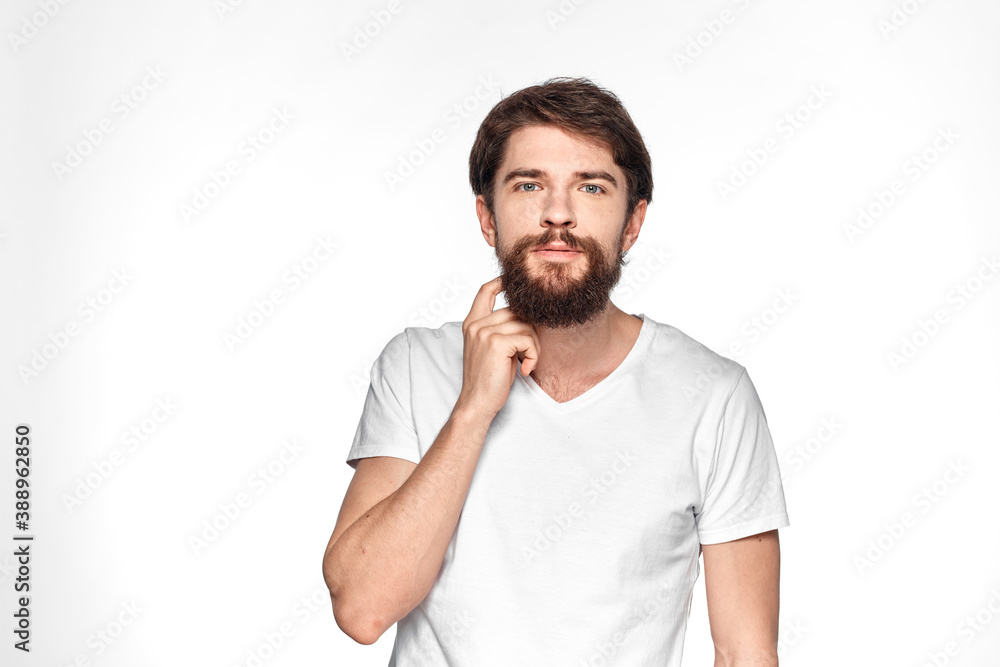 Bearded man in white t-shirt gesture with hands emotions light background Bearded man in white t-shirt gesture with hands emotions light background