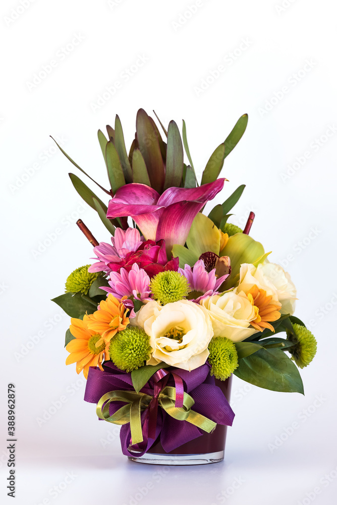 Flower arrangement in a purple vase on white background.