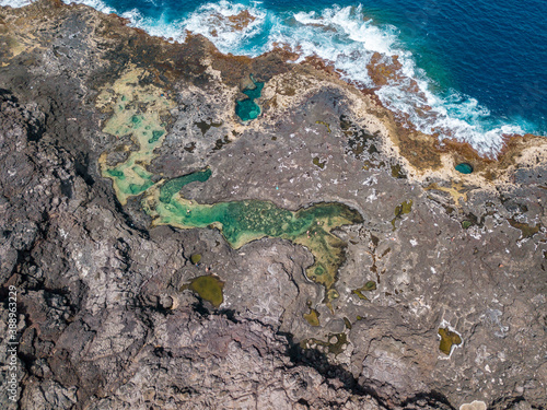 Aerial view of Los Charcones a hidden Lanzarote gem. A stunning natural infinity pool on a lava soil, close the Atlantic ocean. Bathers. Swimming. Canary Islands, Spain photo