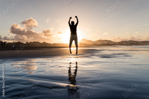 Happy man jumping on the beach with beautiful sunset. Succesful.	