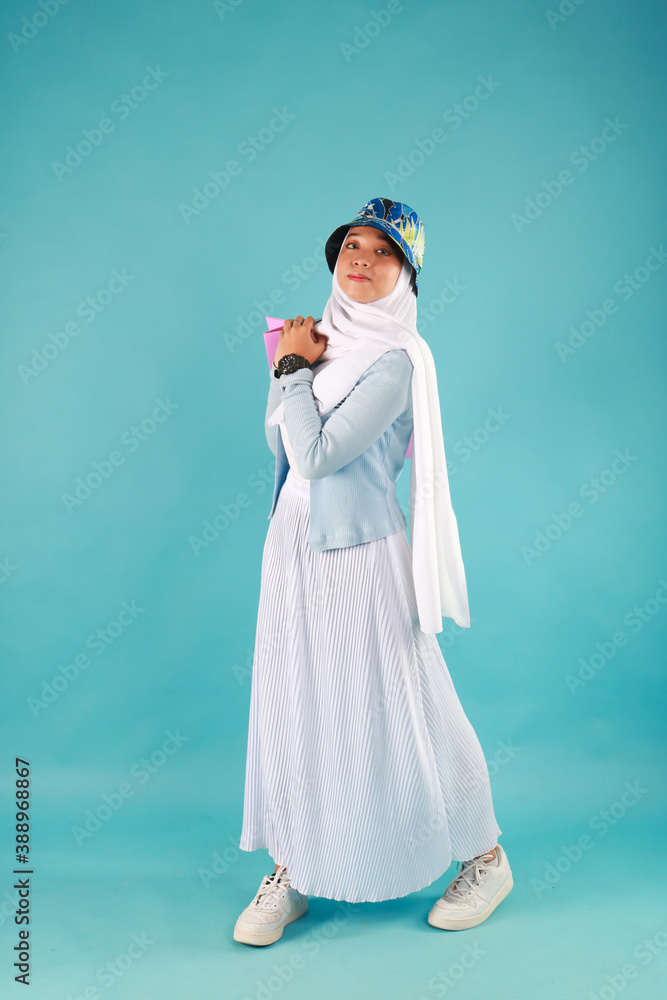 Portrait of an excited beautiful girl wearing dress holding shopping bags isolated over blue background. Portrait of an excited beautiful girl wearing dress holding shopping bags isolated over blue background.
