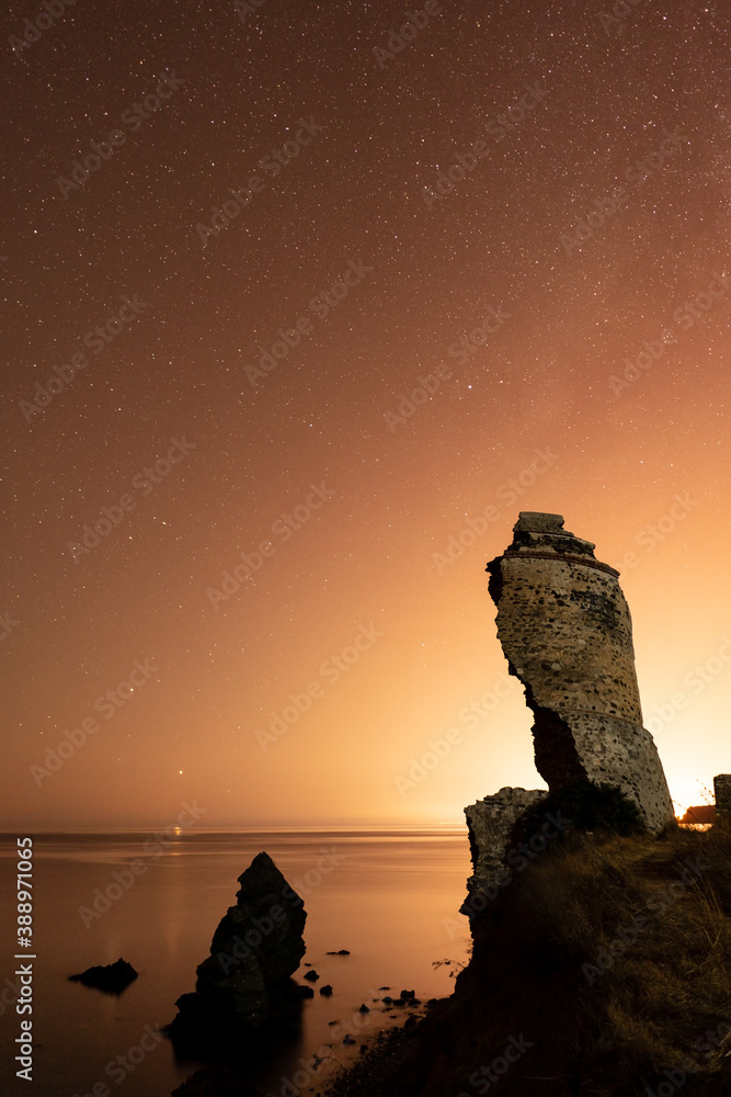 sunset with the sea and stars in the background with a destroyed old tower in the foreground