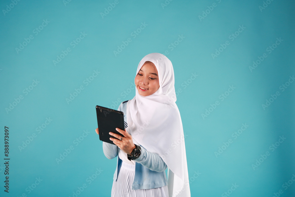 Portrait of a beautiful woman using tablet computer isolated on a blue background. cool winter concept.