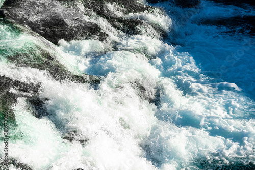 Wild and fast moving river rapids white water rushing over rugged cliffs. Close up.