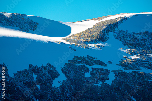 High mountain ridge with rugged cliffs and large patches of glacial snow.