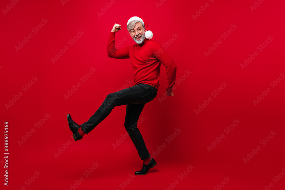 Full-length portrait of bearded old man dancing in new year. Santa claus having fun on red background. Full-length portrait of bearded old man dancing in new year. Santa claus having fun on red background.