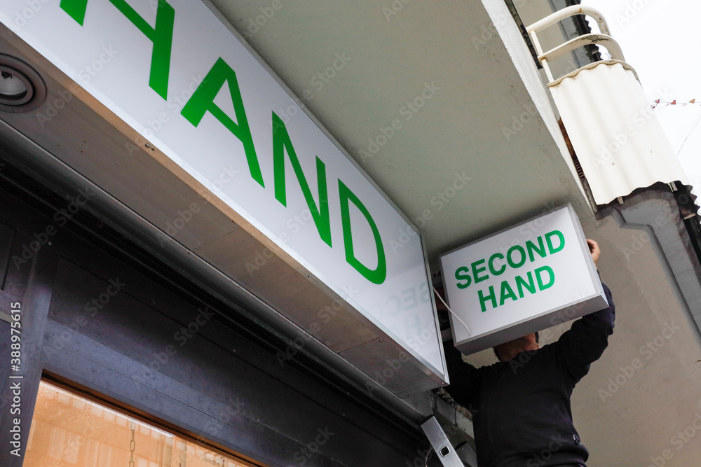 Stockholm, Sweden A man installing a Second Hand sign at a second hand shop. Stockholm, Sweden A man installing a Second Hand sign at a second hand shop.