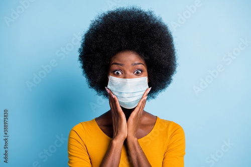 Photo of cute black girl volume hairstyle arms cheeks crazy face wear flu mask yellow shirt isolated blue color background © deagreez