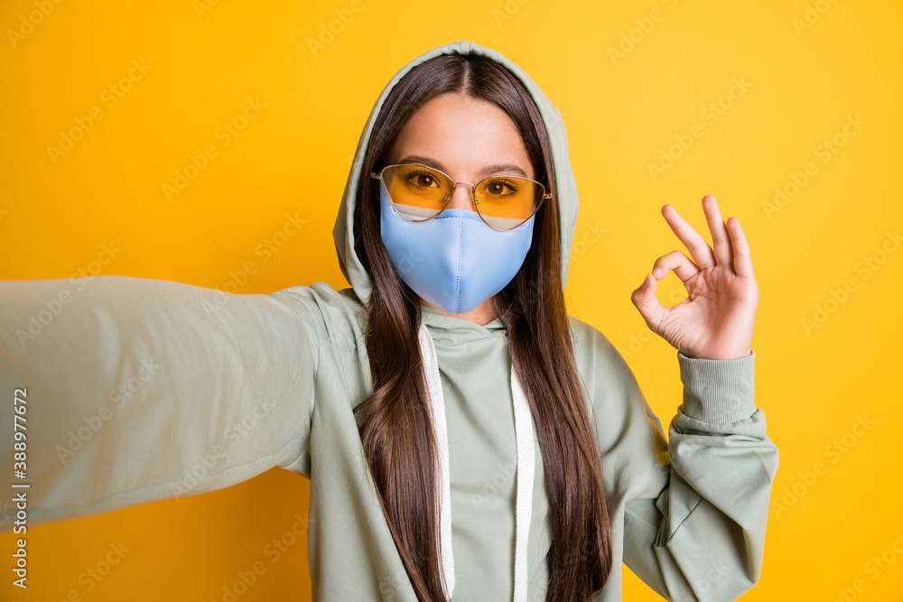Photo of kid show finger okay symbol lifestyle stylish hoodie wear blue fabric face mask isolated on yellow color background Photo of kid show finger okay symbol lifestyle stylish hoodie wear blue fabric face mask isolated on yellow color background