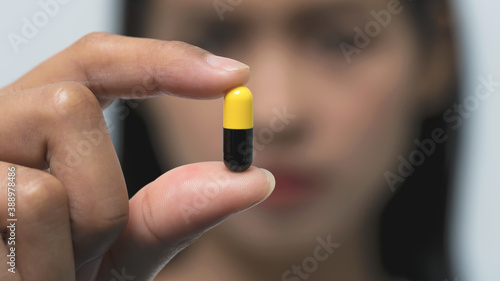 Young Asian woman showing pill in hand to relieve pain concept.