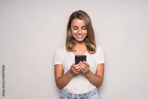 Beautiful woman sending a message with a mobile phone in a white isolated background