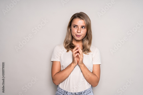 Фотография Portrait of sly woman looking with cunning eyes holding her hands together trying to ask something in sly manner