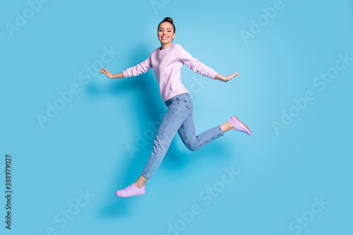 Full length body size profile side view of her she nice attractive pretty glad cheerful cheery girl jumping running enjoying free time isolated bright vivid shine vibrant blue color background © deagreez