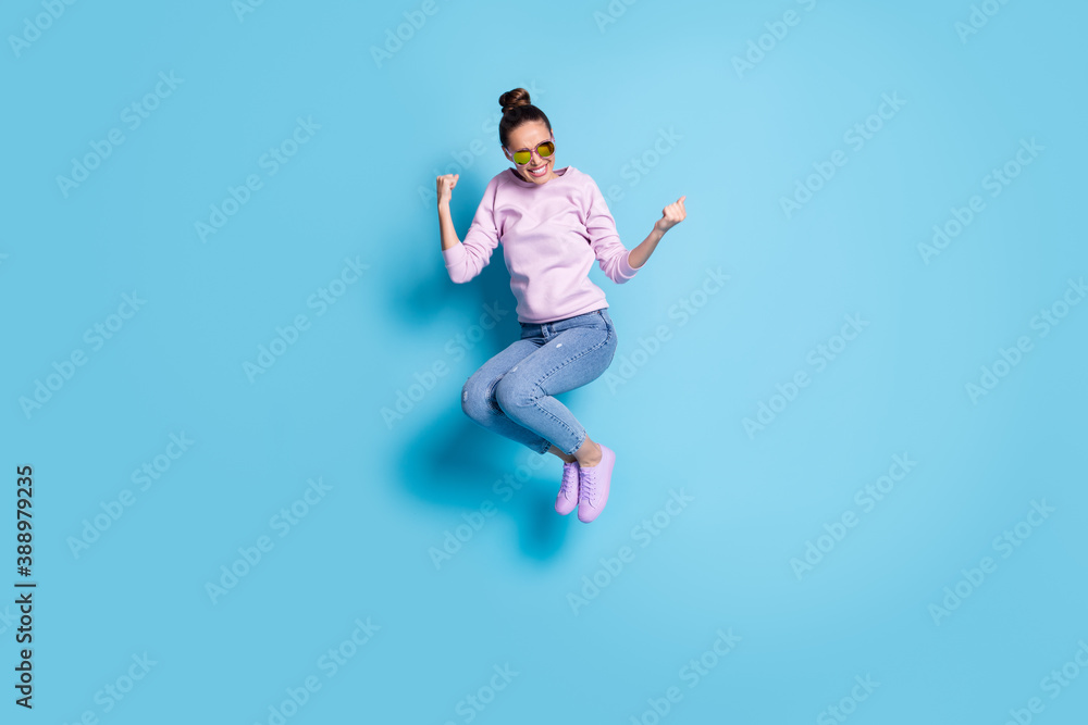 Full length photo of cheerful excited girl jump enjoy rejoice lottery luck discounts win raise fists scream wear violet sweater isolated over blue color background Full length photo of cheerful excited girl jump enjoy rejoice lottery luck discounts win raise fists scream wear violet sweater isolated over blue color background