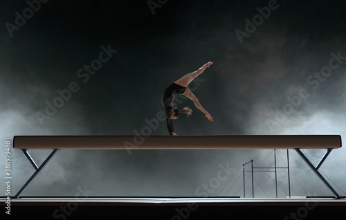 Schilderij op canvas Female gymnast doing a complicated trick in a professional arena.