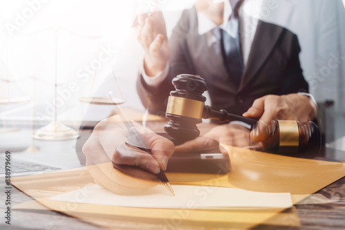 Justice and law concept.Male judge in a courtroom with the gavel, working with, computer and docking keyboard, eyeglasses, on table in morning light