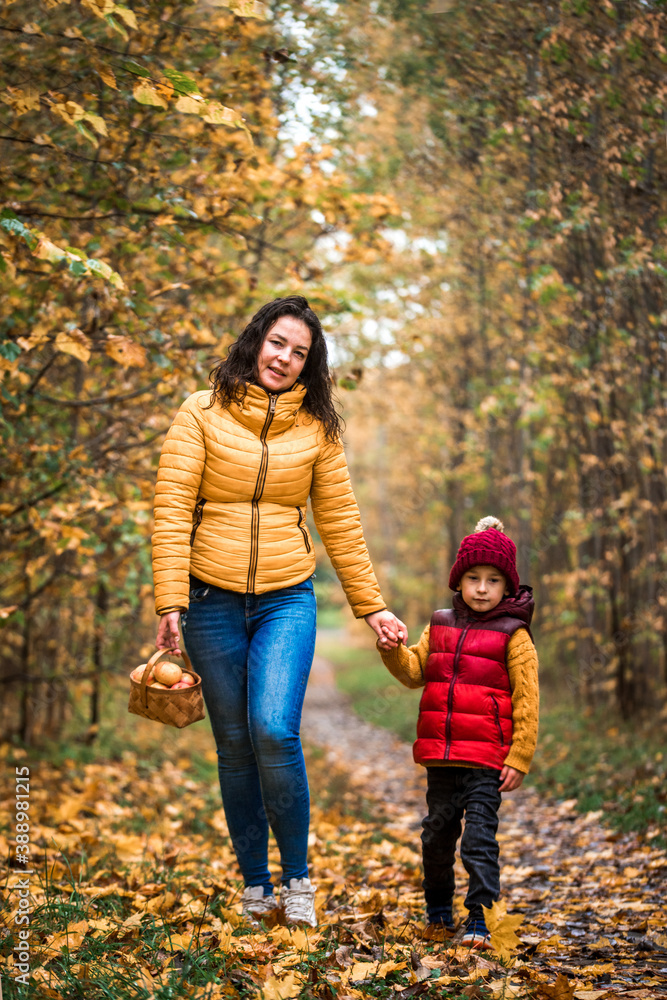 Young mother with her little baby boy having fun in the autumn park