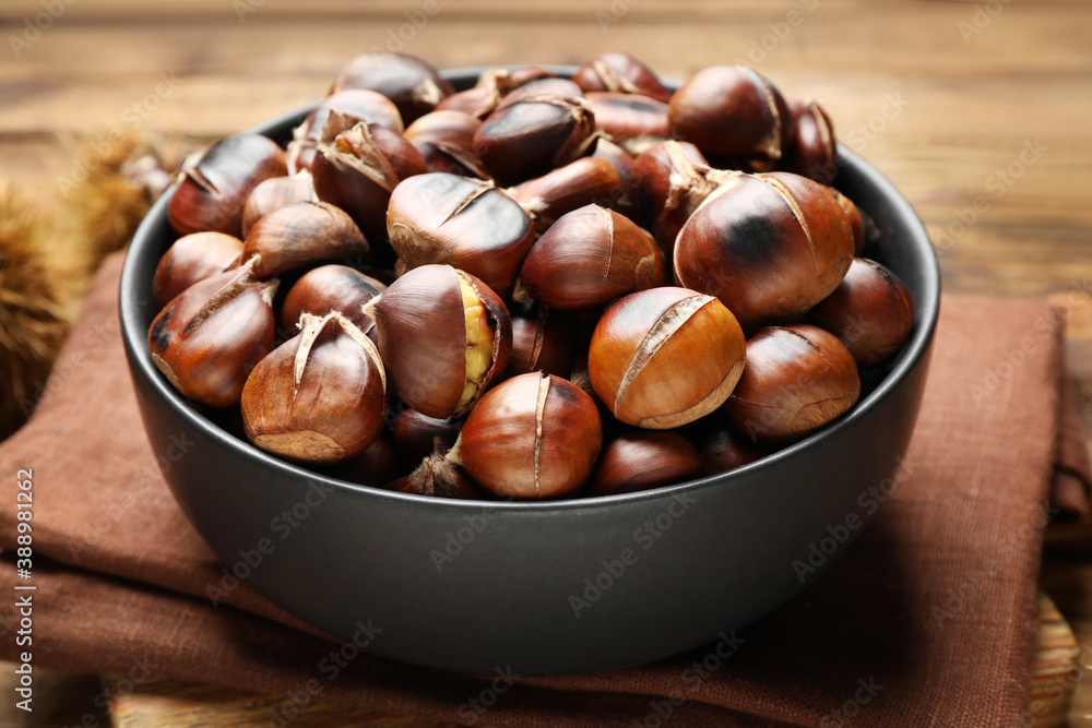 Delicious roasted edible chestnuts in bowl on table, closeup Delicious roasted edible chestnuts in bowl on table, closeup