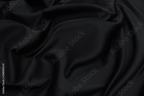 Smooth elegant black silk satin fabric texture  as abstract background. Luxurious pattern for design.