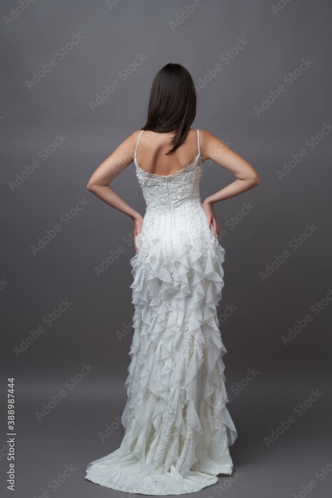 Fototapeta premium Beautiful bride in wedding dress posing on grey background