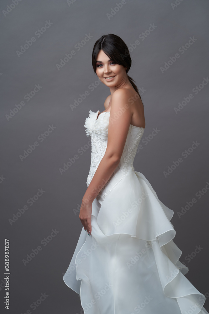 Beautiful bride in wedding dress posing on grey background Beautiful bride in wedding dress posing on grey background