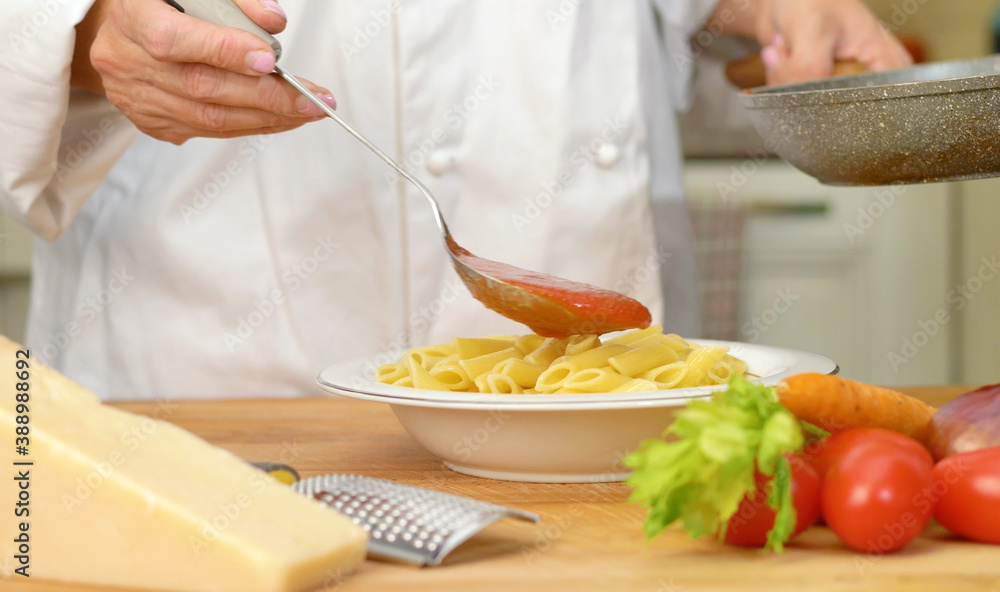 mixing penne and tomatoes sauce in the dish mixing penne and tomatoes sauce in the dish