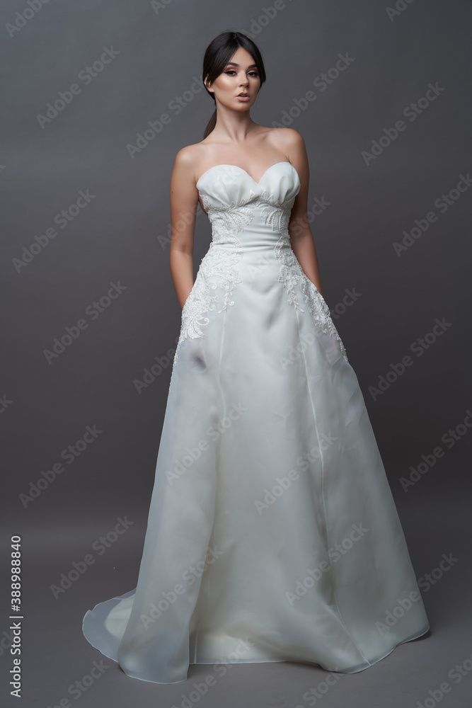 Beautiful bride in wedding dress posing on grey background with copy space.