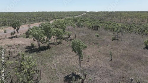 Aerial drone shot moving through trees opening to a long straight highway in Northern Territory, Australian Outback photo