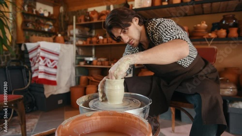 Ceramist uses potter's wheel and creates a handmade clay product. photo