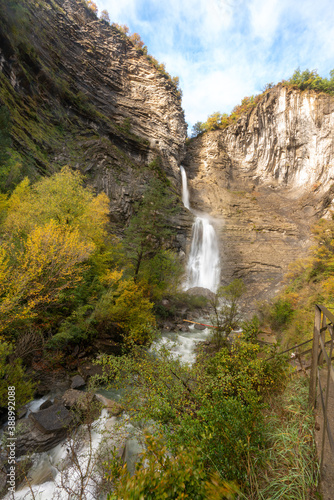 Upright photography of Cascada de Sorrosal (Sorrosal waterfall) with yellow autumn trees foreground in Broto ,Spain