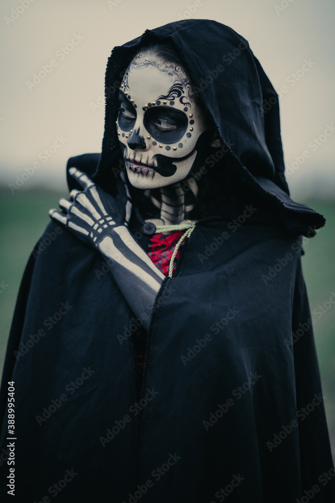 Portrait of woman in Halloween costume of death with painted skeleton on her body and sugar skull makeup.