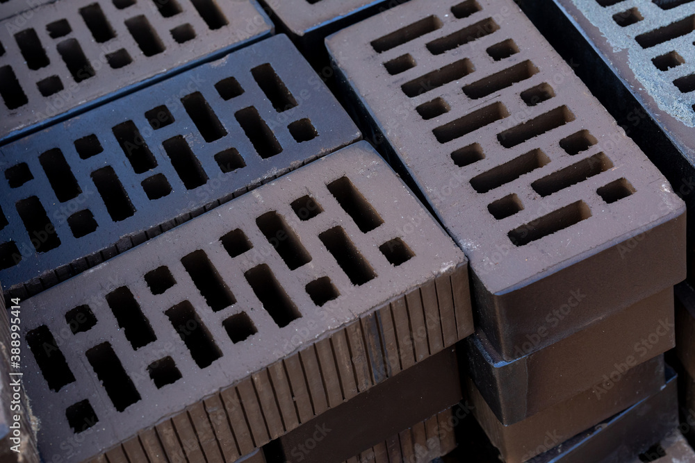 A stack of dark brown hollow bricks at a construction site at sunset.