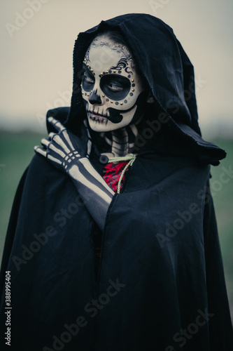 Portrait of woman in Halloween costume of death with painted skeleton on her body and sugar skull makeup.