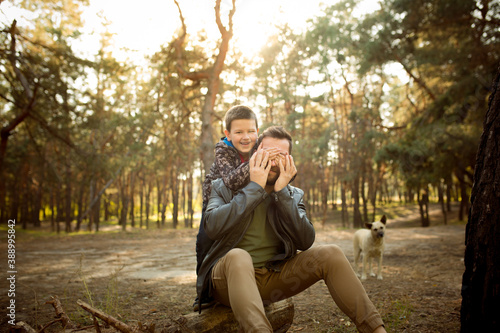 Hugging. Father and son walking and having fun in autumn forest, look happy and sincere. Laughting, playing, having good time together. Concept of family, happiness, holidays, childhood, lifestyle. © master1305