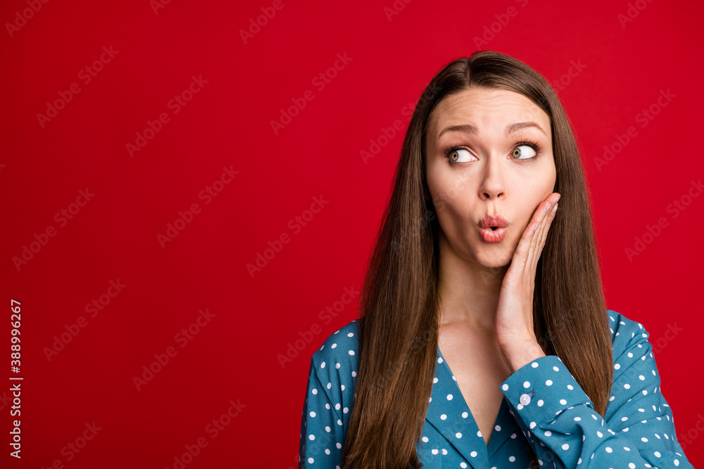 Fototapeta premium Close-up portrait of pretty amazed brown-haired girl looking aside pout lips copy space isolated over bright red color background