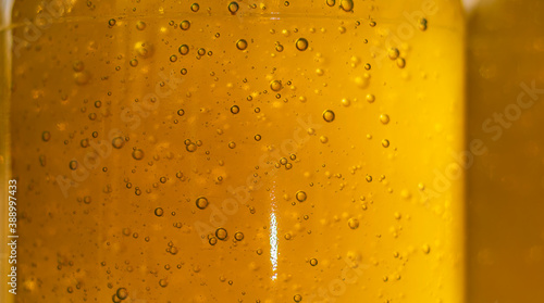 Bee honey texture with air bubbles behind glass